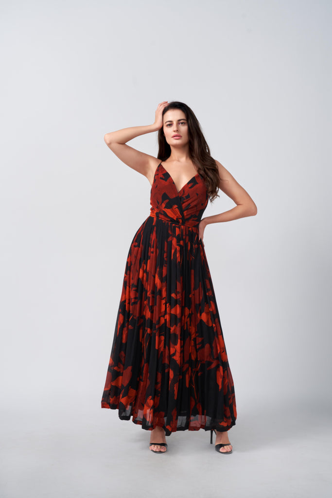 Model posing front-facing in the red and pink abstract floral gathered flare dress with one hand raised