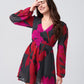 Close-up of smiling model in chinon short dress with bold floral print and voluminous puff sleeves.