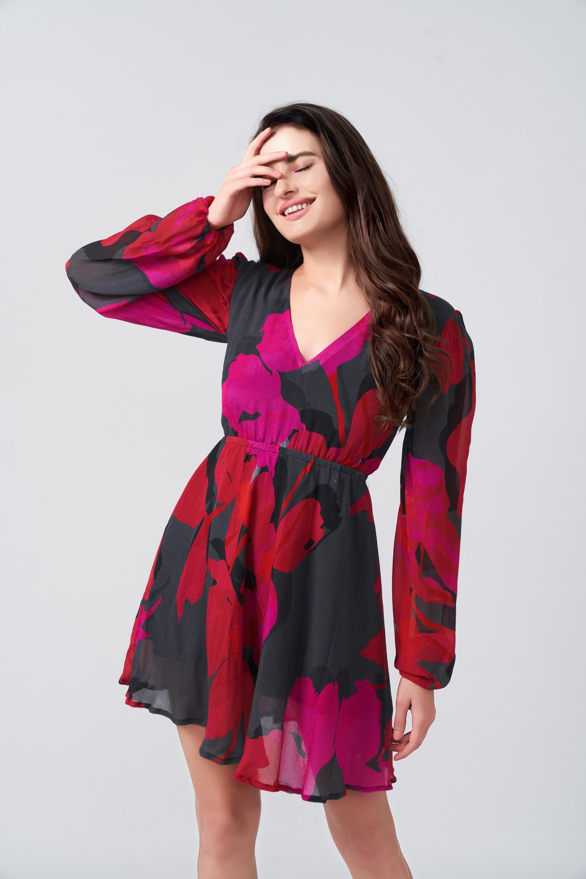 Close-up of smiling model in chinon short dress with bold floral print and voluminous puff sleeves.