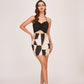 Angled walk-forward pose of the model in black printed mini dress with ruched top and flared hem.