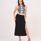 Model in a confident front-facing pose wearing the abstract printed white top and black thigh-high slit skirt.