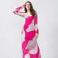 Woman modeling a pink and white abstract print ankle-length dress, standing against a plain white background.