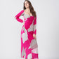 Woman in a pink and white abstract print ankle-length dress, posing with one hand on her hip