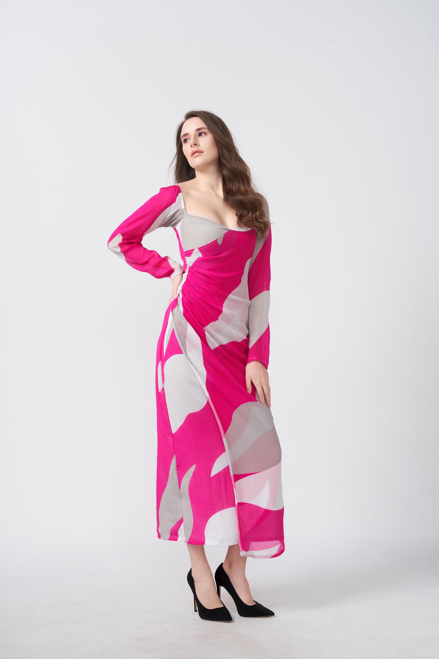 Woman in a pink and white abstract print ankle-length dress, posing with one hand on her hip