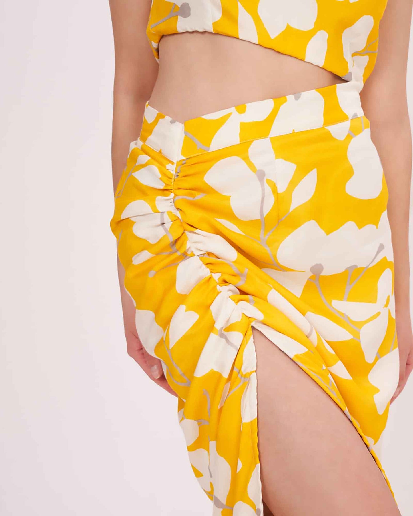 Close-up of the yellow printed co-ord set focusing on the side slit, ruched skirt detailing, and waistline fit.