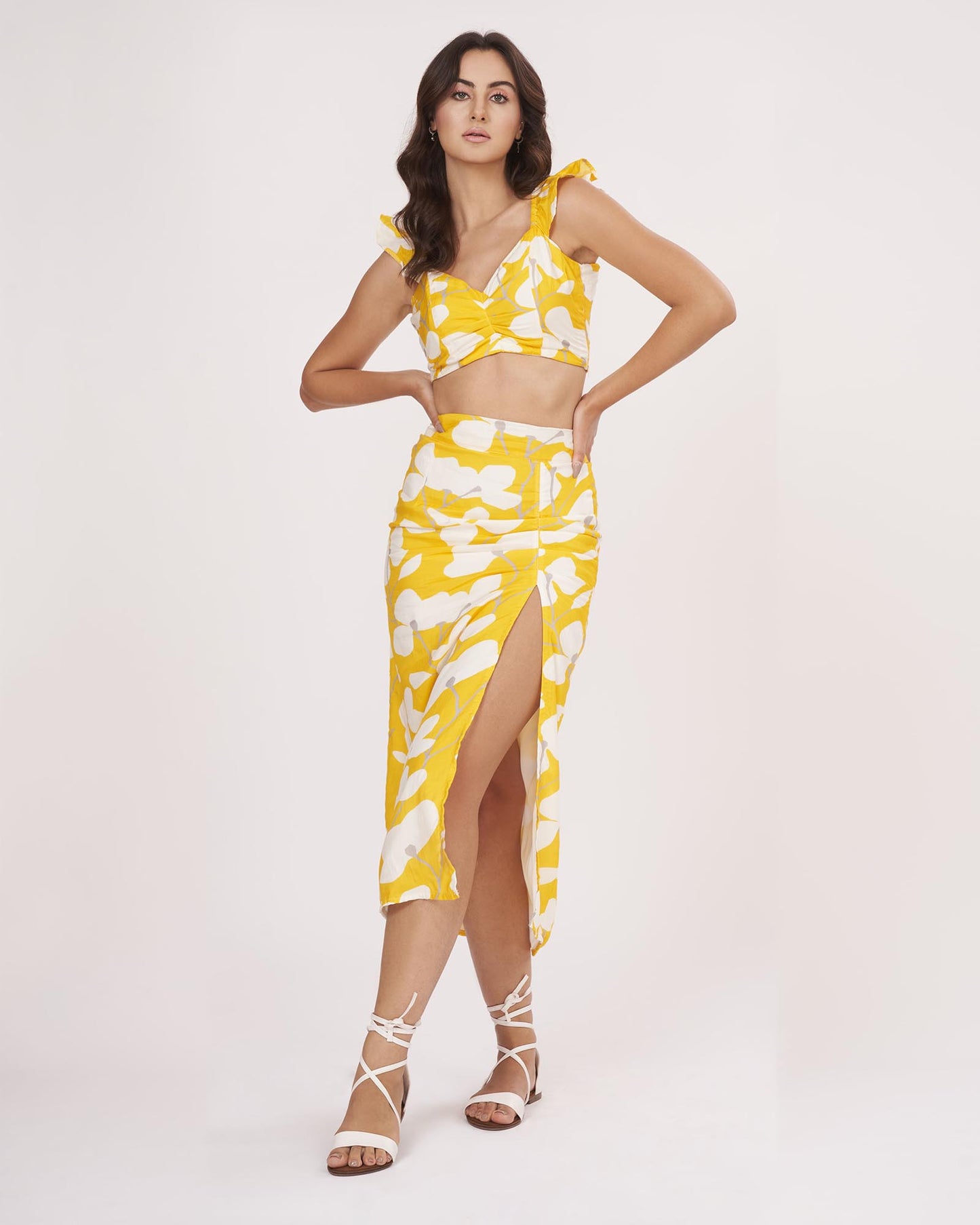 Model stands confidently with hands on waist wearing the floral yellow muslin co-ord set, highlighting the thigh-high slit and fitted silhouette