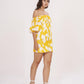 Side view of model in yellow off-shoulder short dress with ruched puff sleeves and relaxed fit.