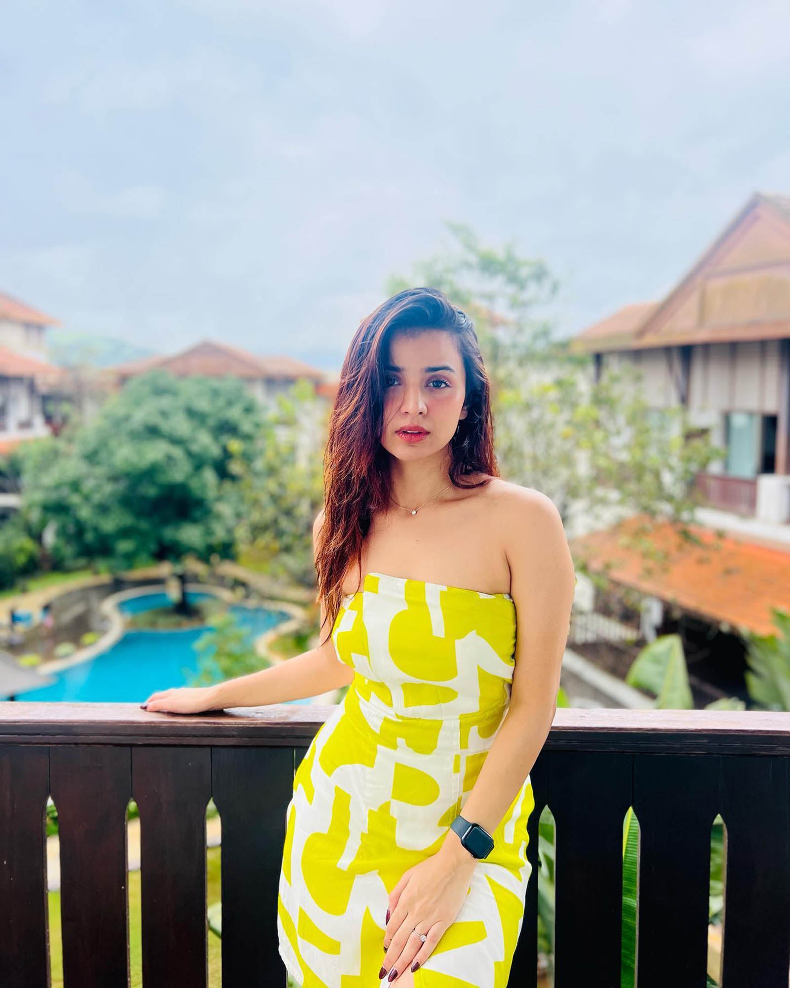 Model in the outdoors in the yellow printed dress, emphasizing the strapless neckline and vacation-ready feel.