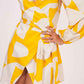 Close-up of yellow abstract satin dress showing tie-up waist and sleeve texture.