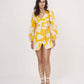 Walking pose of model in yellow printed wrap dress, showcasing movement and fit.