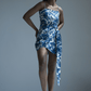 Full front-facing view of model in blue printed wrap-style dress, standing straight with arms by side.