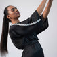 Side view of black kimono mini dress with one hand raised and lace hem visible.