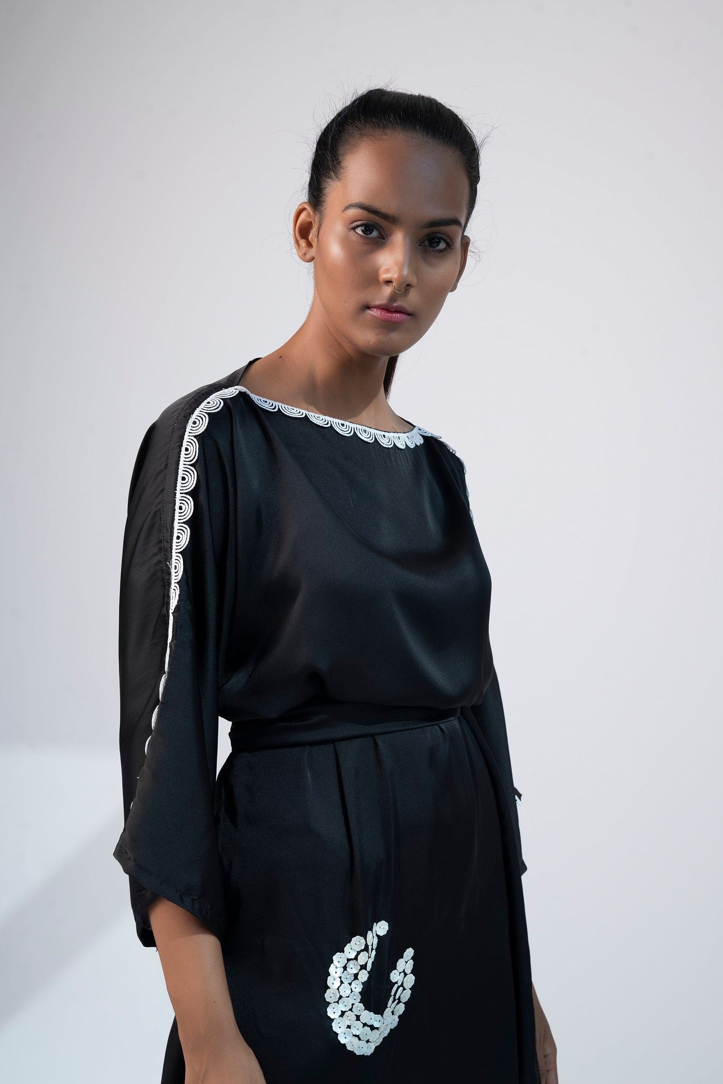 Close-up of black mini kimono dress with boat neck, shell embroidery, and kimono sleeves.