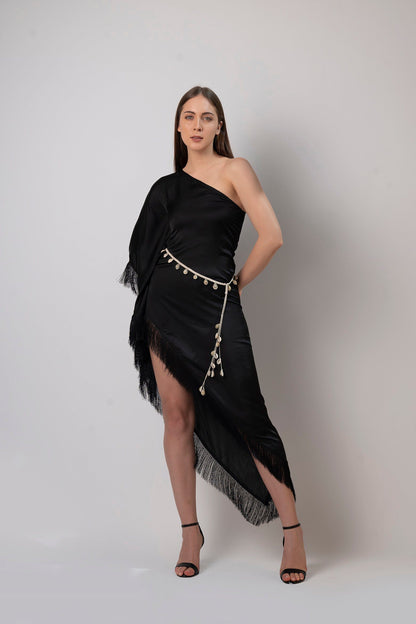 Studio front pose of black kaftan dress highlighting the one-shoulder sleeve and tassel detailing.
