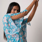 Close-up of model lifting arm in blue georgette dress showing slit sleeve and seashell detailing.