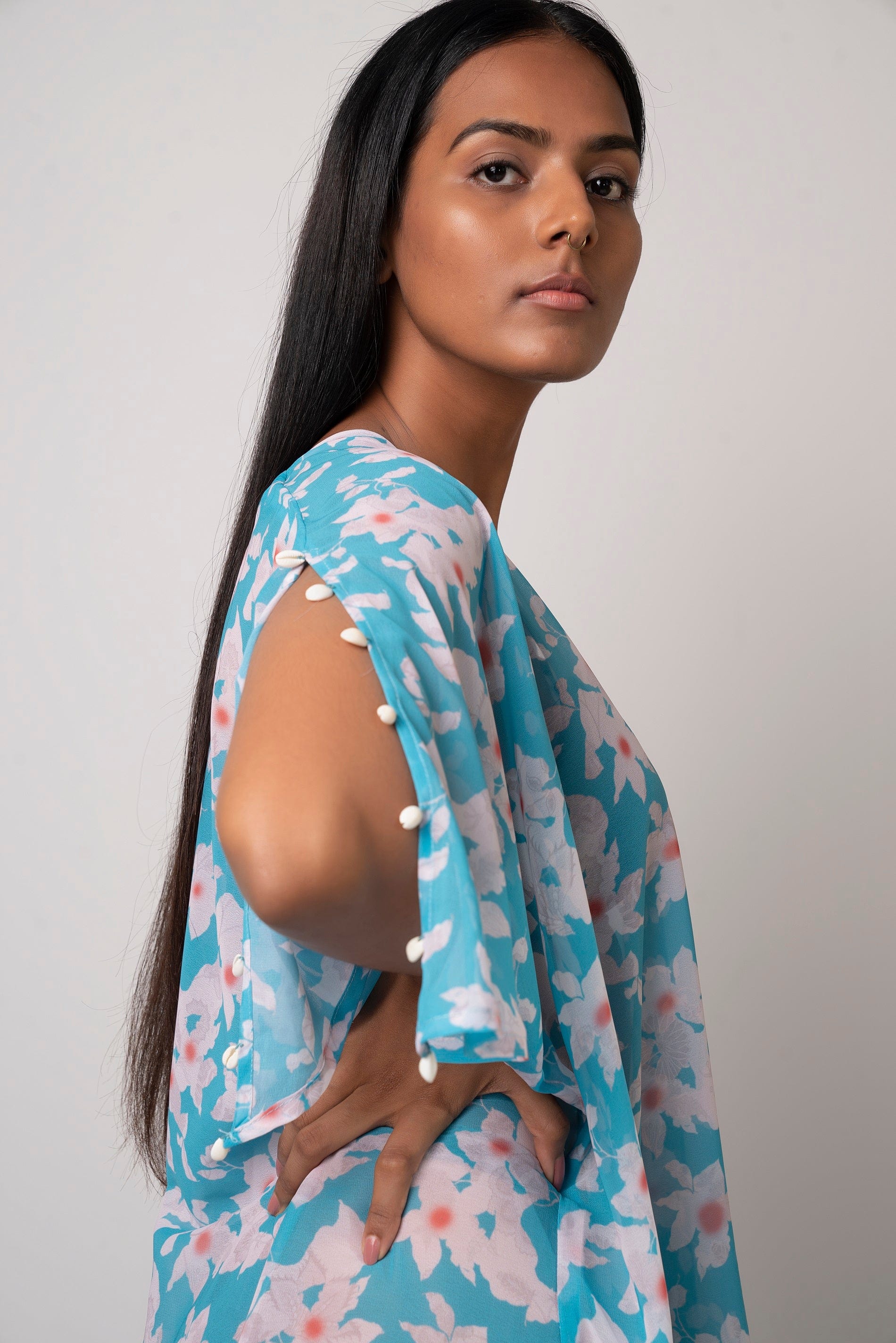 Side profile of blue printed multiway dress highlighting sea shell embellishments on slit sleeves.