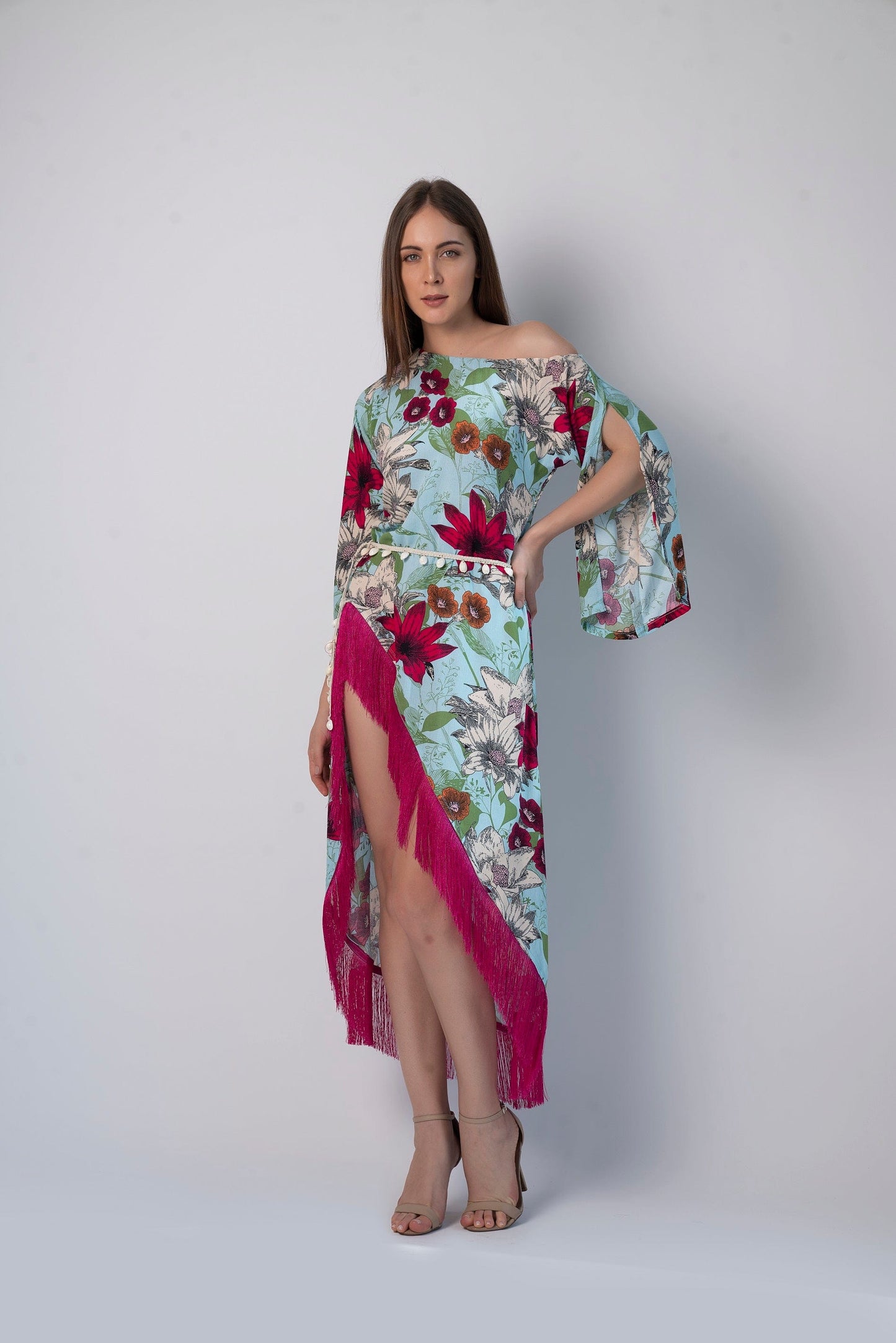 Walking pose of model in asymmetric hem beach dress with playful fringes and bohemian print, hands gently at sides.