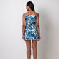 Model in rear-facing stance of blue printed dress showing back fit and shoulder strap detailing.