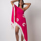 Model poses with both arms raised wearing a pink one-shoulder georgette kaftan dress adorned with shell embroidery and fringe