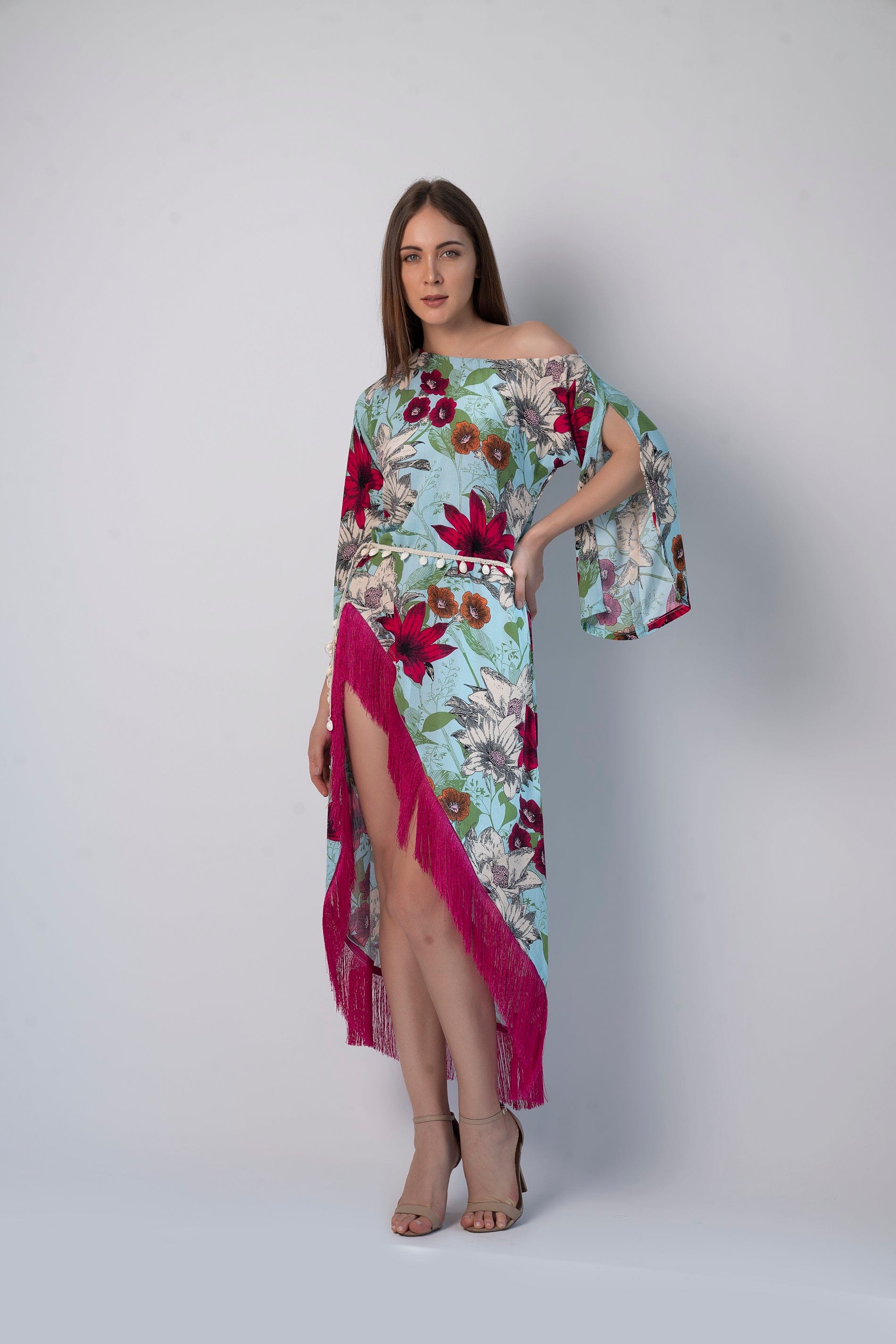 Walking pose of model in asymmetric hem beach dress with playful fringes and bohemian print, hands gently at sides.