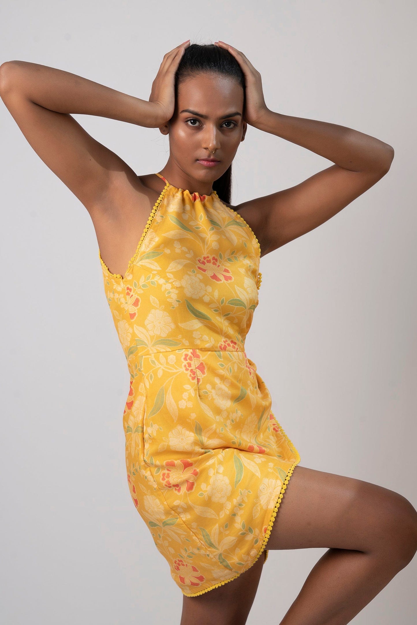 Model pose with hands on head, showcasing the sleeveless halter neck design and wrap-style silhouette.