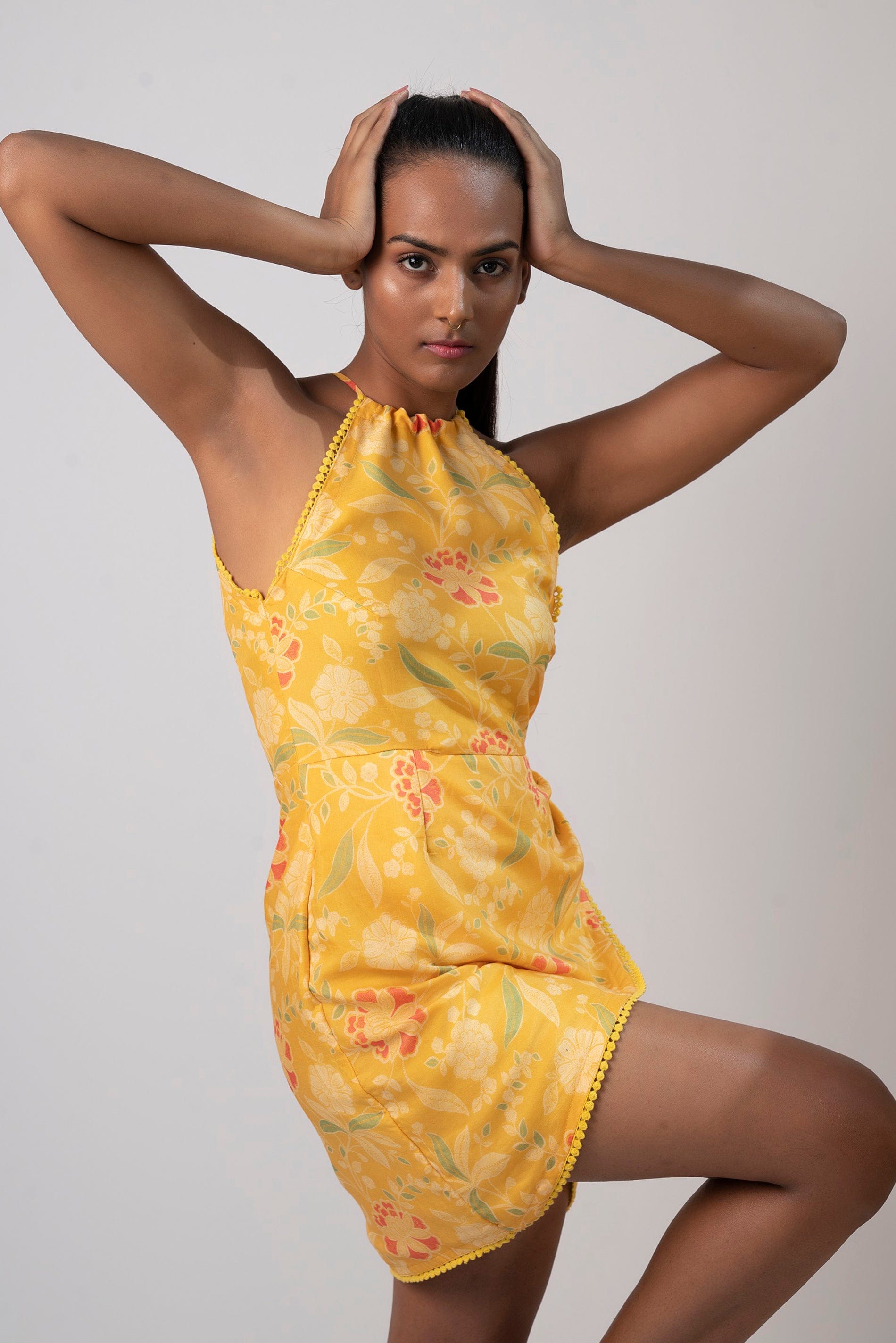 Model pose with hands on head, showcasing the sleeveless halter neck design and wrap-style silhouette.