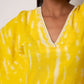 Neckline close-up of yellow kimono cotton dress highlighting lace trim and sea shell embellishments.
