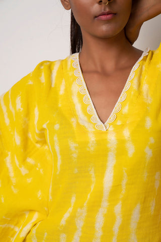 Neckline close-up of yellow kimono cotton dress highlighting lace trim and sea shell embellishments.