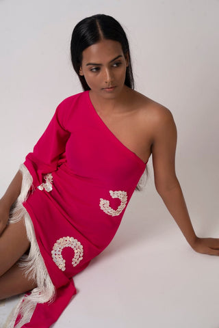 Model seated in a relaxed pose in the pink embroidered georgette dress, accentuating the flowy fabric, one-shoulder cut, and breezy beachwear feel.