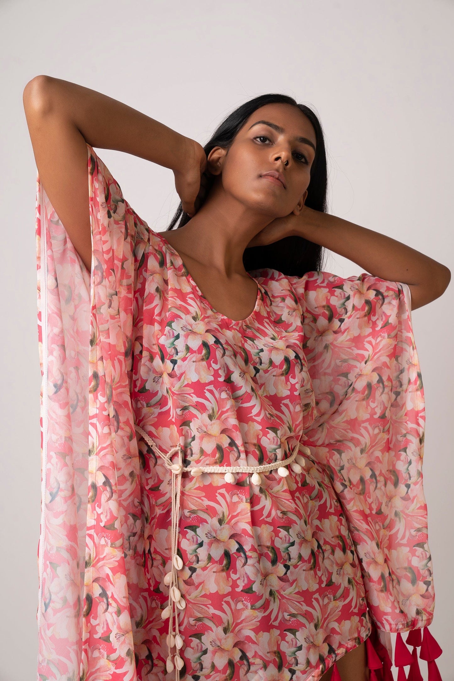 Close-up front view of model wearing pink floral georgette dress with shell belt