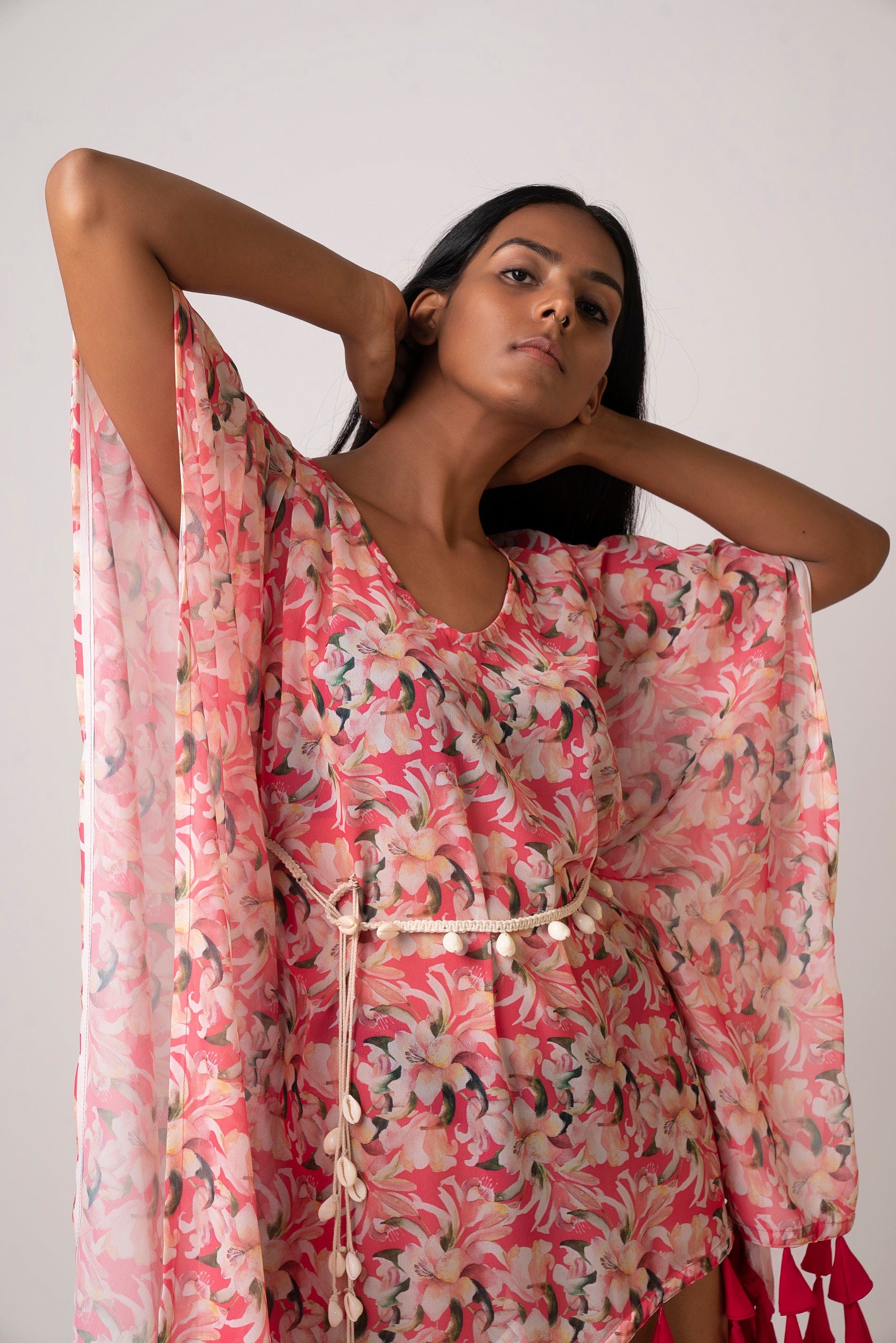 Close-up front view of model wearing pink floral georgette dress with shell belt
