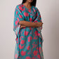 Front view of model in flowy floral kaftan with V-neckline and cinched waist tie, showcasing relaxed silhouette.