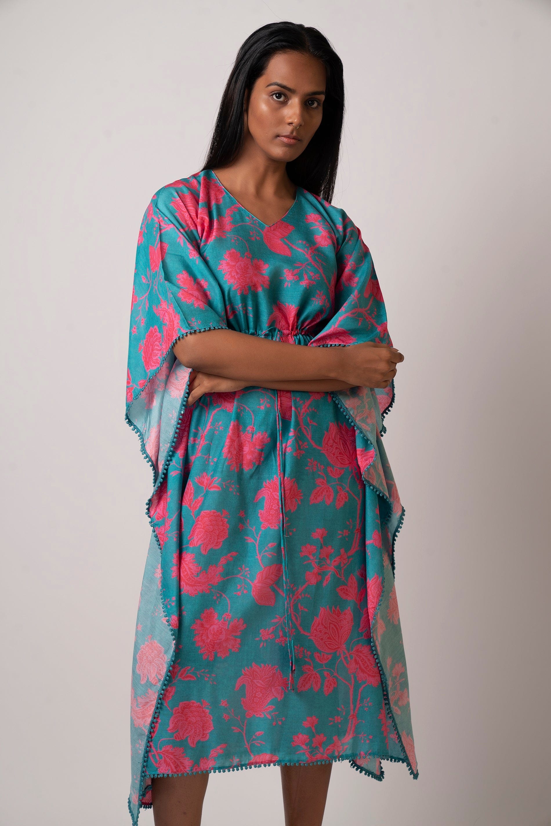 Front view of model in flowy floral kaftan with V-neckline and cinched waist tie, showcasing relaxed silhouette.