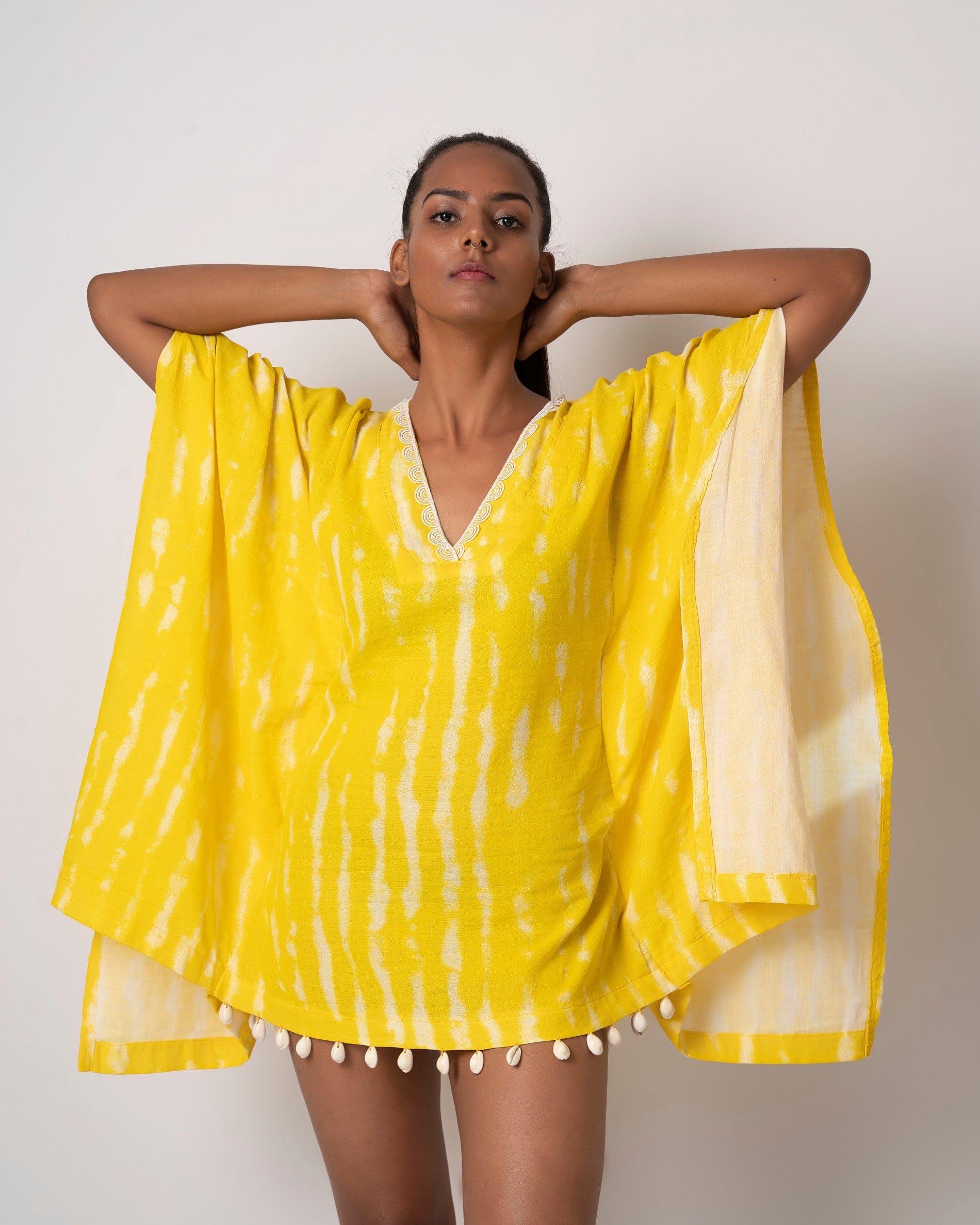 Yellow tie-dye cotton kaftan dress with lace and shell details, ideal for beach vacations and resort wear