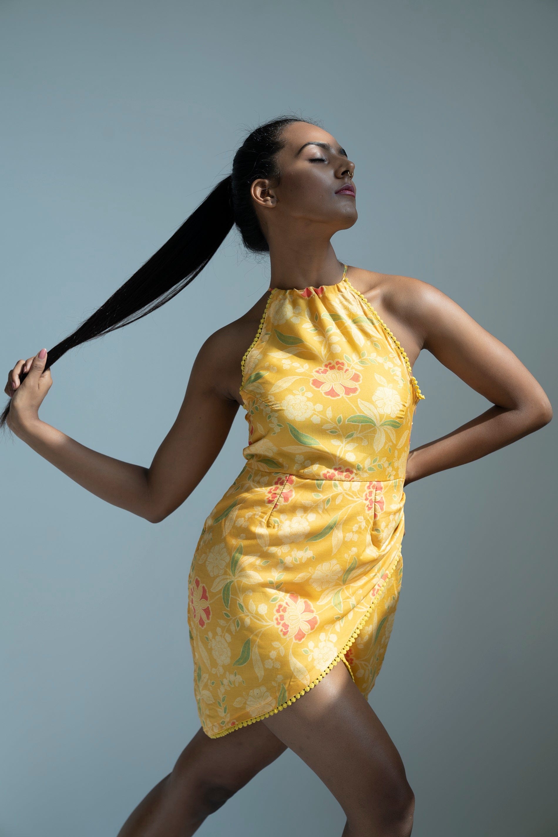 Side-angle standing pose of model flaunting lace-trimmed hemline and the dress’s contouring wrap style.